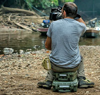 Photographer sat on an explorer taking a picture next to a river