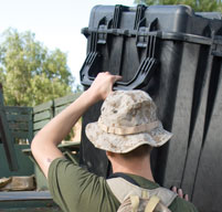 a man with a hat lifting a 0500 transport case using the Double wide grip fold down handles