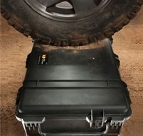 black Peli Case under a wheel of a car