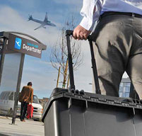 a man walking toward an airport with a plane in the sky pulling a Peli IM2435 Storm case